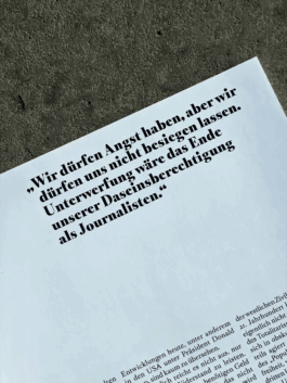 Zitat aus der Publikation ‚Fotos für die Pressefreiheit 2025‘ von Reporter ohne Grenzen. In großer Typografie steht: ‚Wir dürfen Angst haben, aber wir dürfen uns nicht besiegen lassen. 