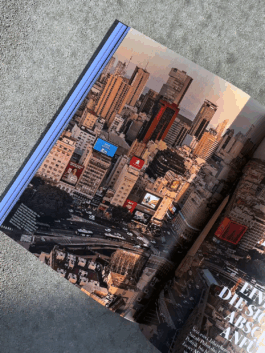 Fotografie eines Artikeleisntiegs aus der Publikation ‚Fotos für die Pressefreiheit 2025‘ von Reporter ohne Grenzen. Gezeigt wird eine Panoramaaufnahme der Fotografin Sarah Pabst von Buenos Aires mit Fokus auf die Avenida 9 de Julio und umliegende Hochhäuser. 