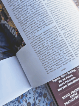 Detailaufnahme einer aufgeschlagenen Publikation ‚Fotos für die Pressefreiheit 2025‘ von Reporter ohne Grenzen. Sichtbar ist ein Interviewtext mit dem Länderfokus Uganda. Darunter liegt das Cover der Publikation mit dem Titel und beteiligten Fotograf:innen. 